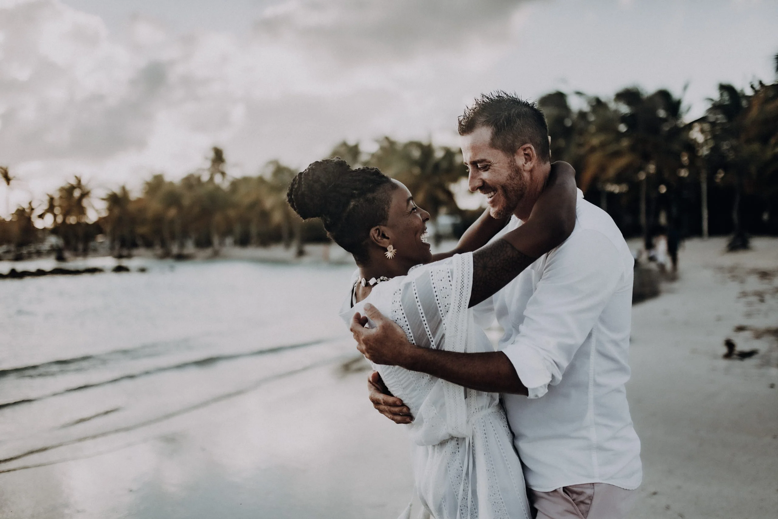 Séance couple sur la plage de Sainte-Anne – C & S 06 Couple dansant sur une plage de sable blanc à Sainte-Anne en Guadeloupe, sous un ciel nuageux