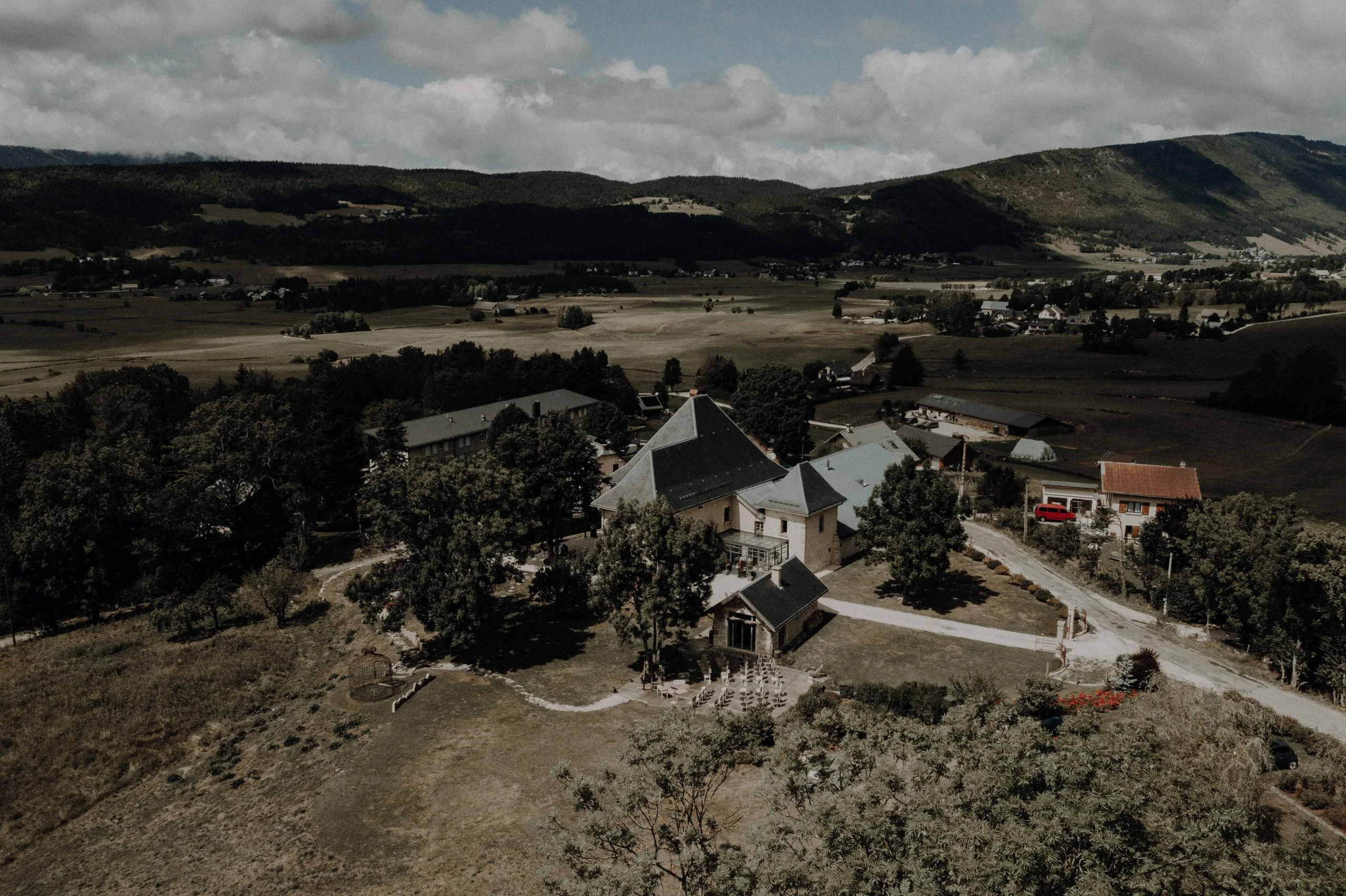 Château des Girards - Vue panoramique sur le domaine Vue aérienne d'un domaine entouré de collines, de prairies et de végétation dans un paysage rural.