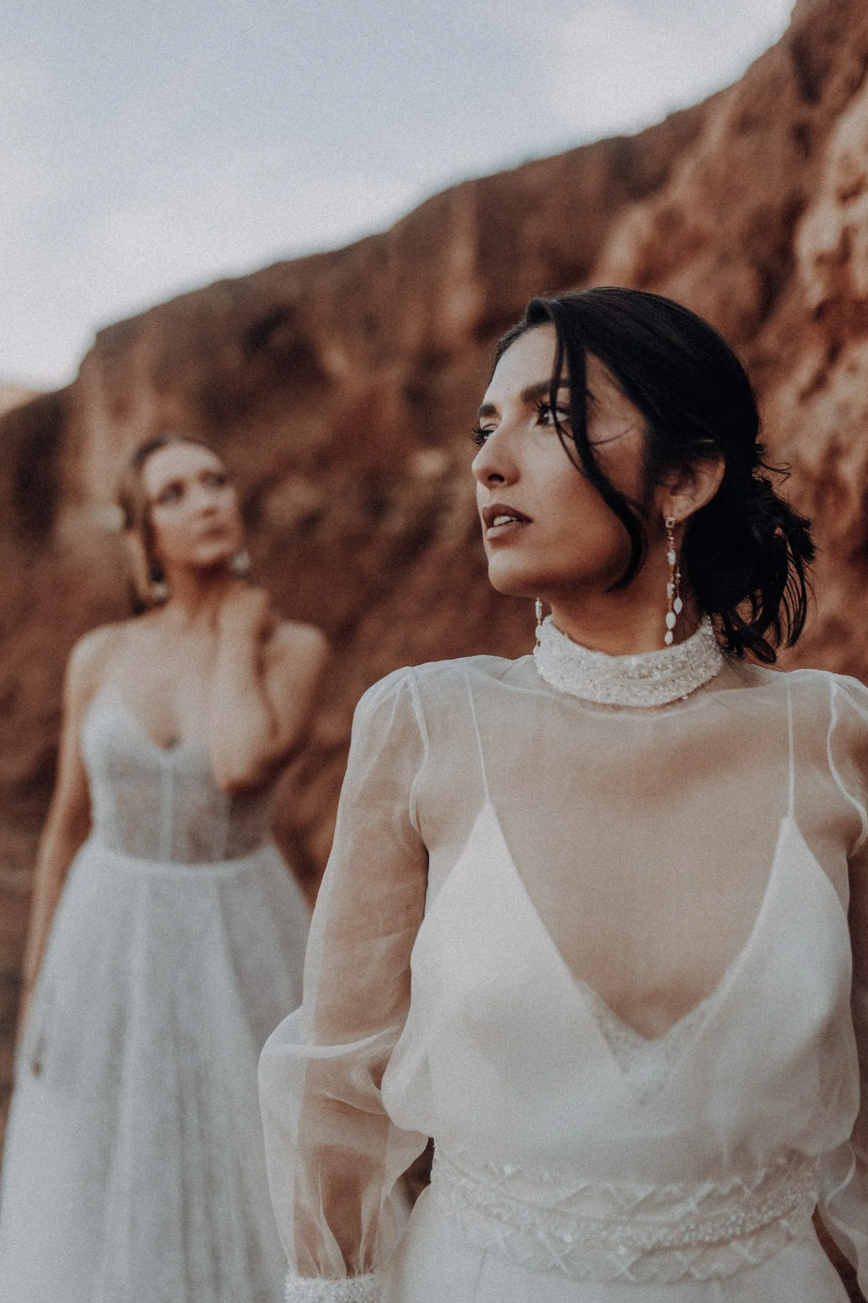 Portrait rapproché d'une mariée en robe blanche devant des roches ocres au Maroc