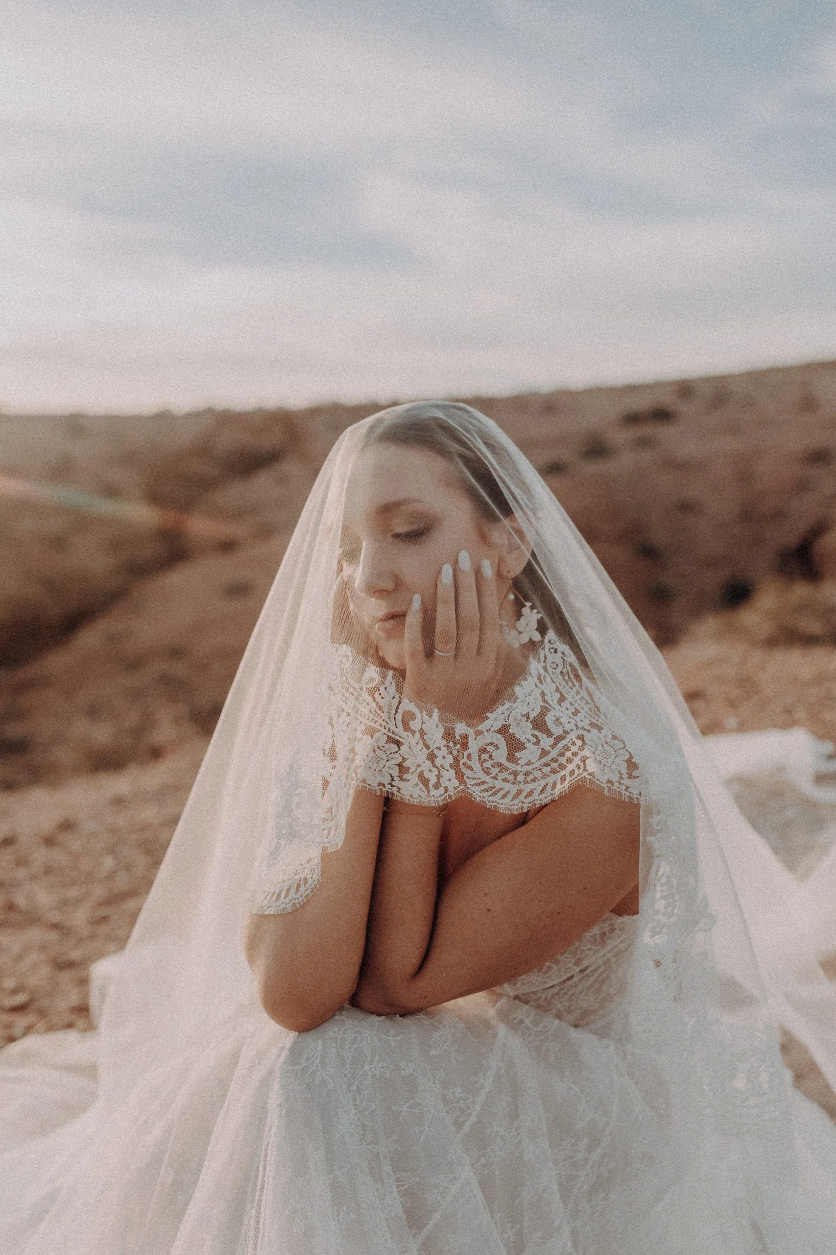 Portrait doux d'une mariée portant un voile dans un paysage désertique marocain
