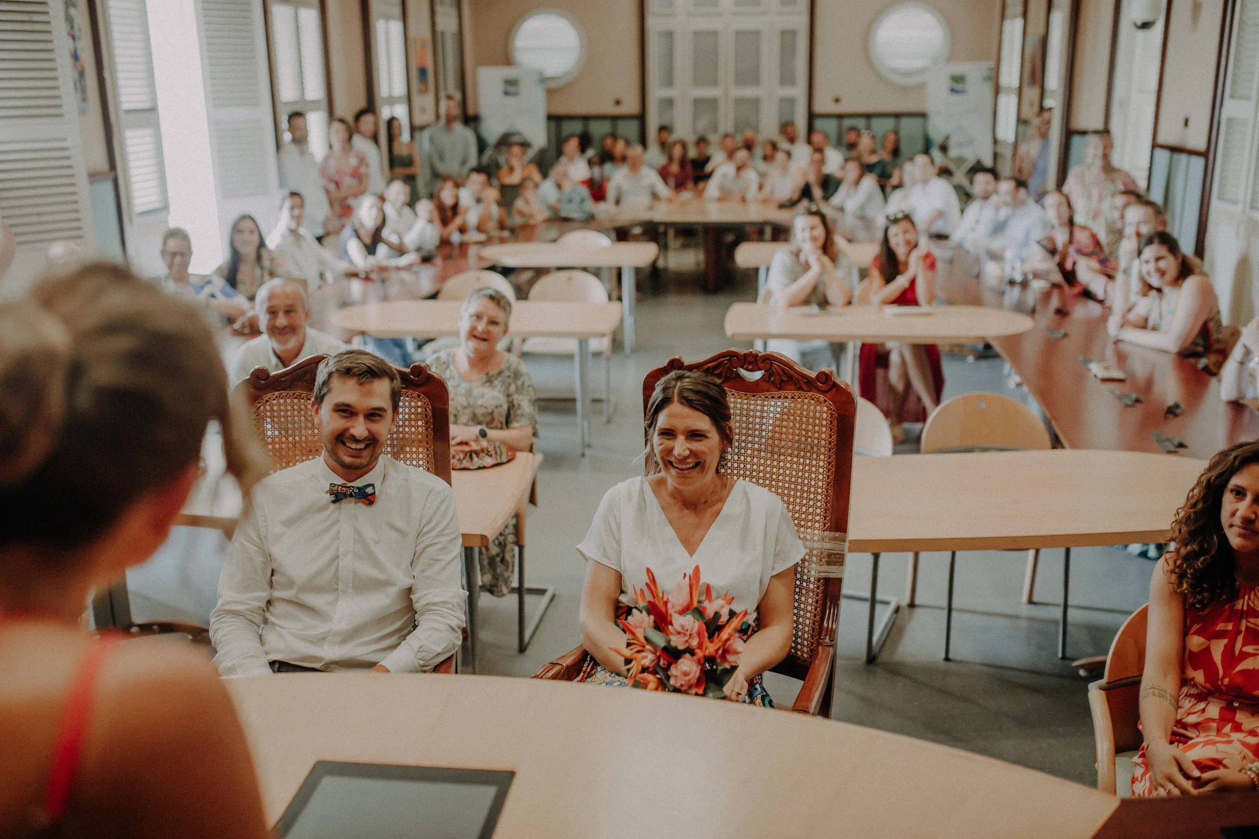 Solène et Mathieu assis à la mairie du Lamentin avec leurs invités en arrière-plan