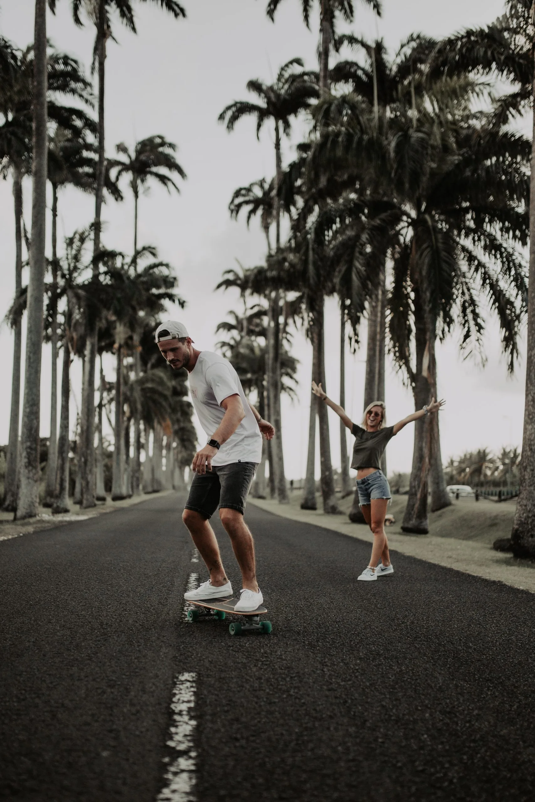 Couple jouant sur la route bordée de palmiers royaux de l'Allée Dumanoir
