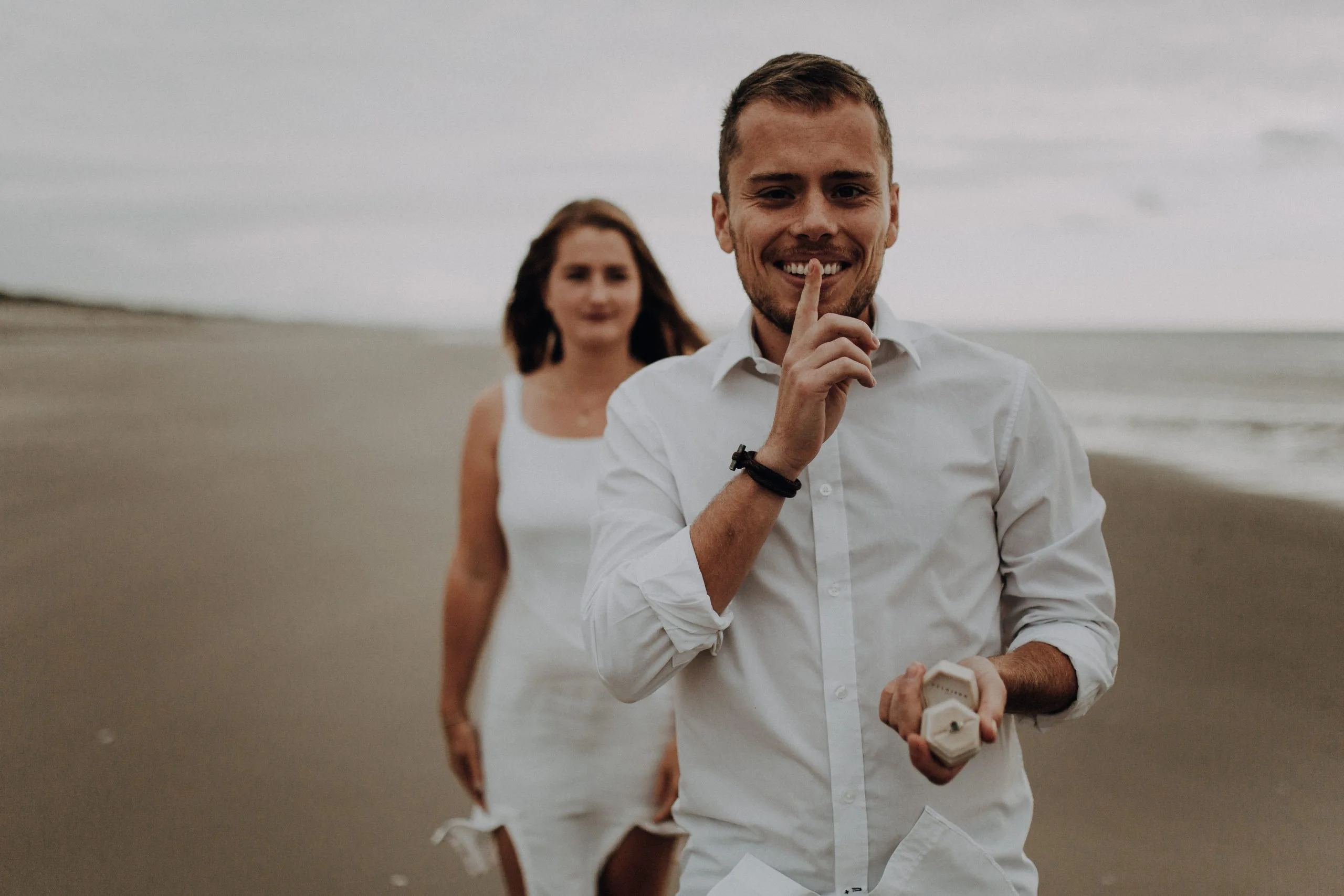 Portrait d'un homme en chemise blanche au premier plan et de sa compagne sur la plage du Touquet