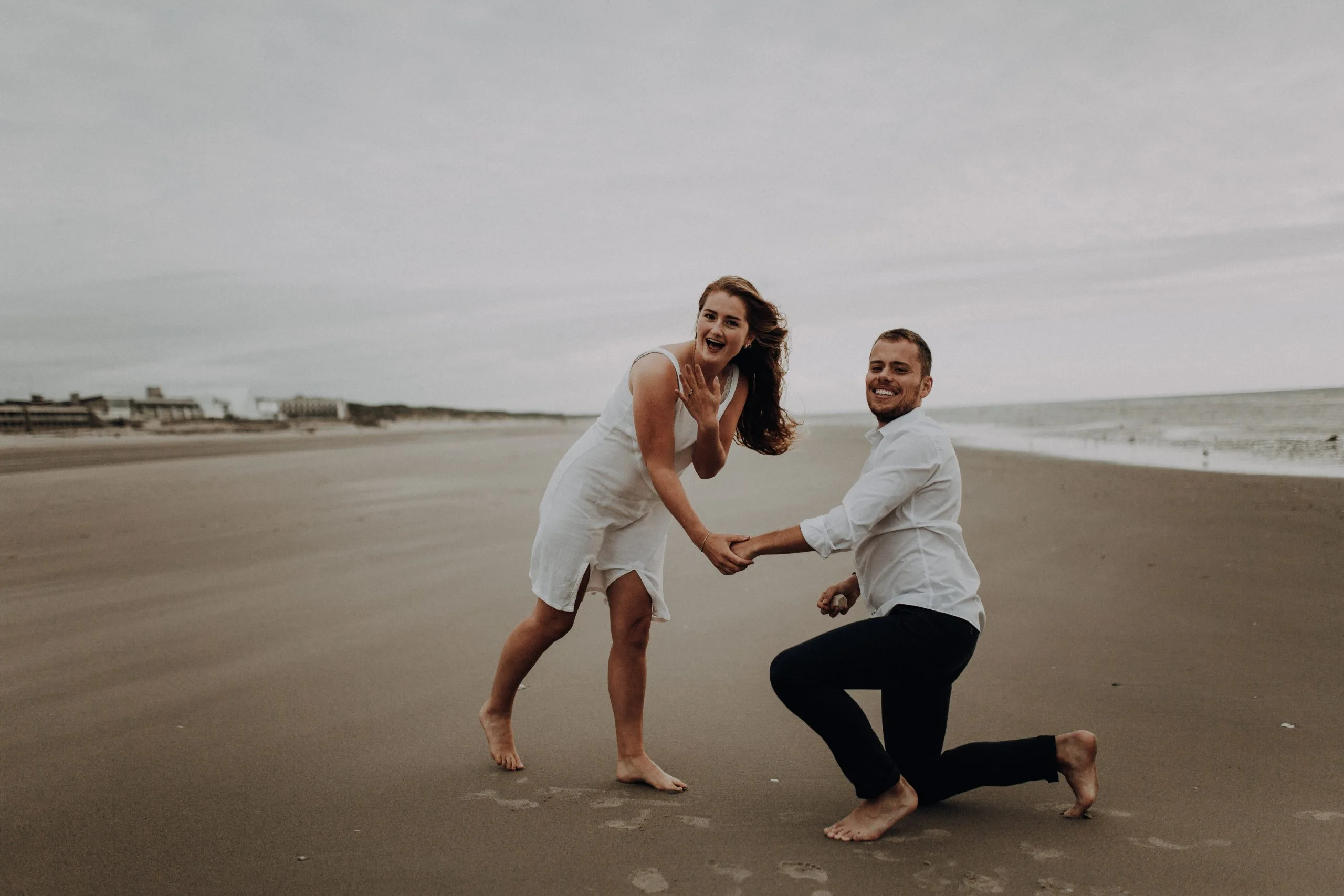 Couple se tenant les mains et jouant sur la plage du Touquet, avec la mer en arrière-plan