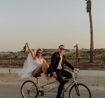 Couple se promenant main dans la main dans un paysage aride avec des palmiers.