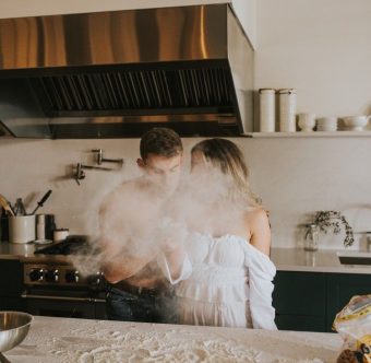 Couple s'amusant avec de la farine dans une cuisine lors d'une préparation culinaire.