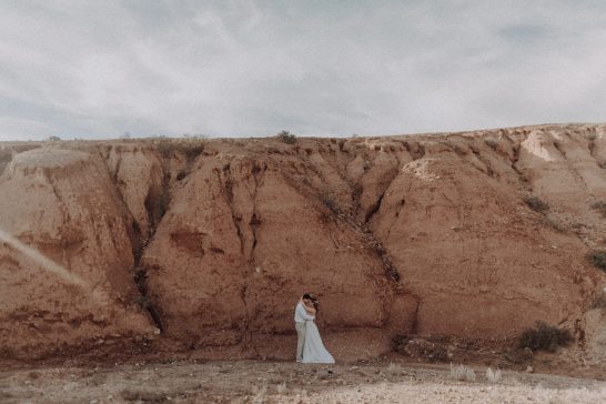 Mariés photographiés dans un vaste paysage de falaises rocheuses aux tons ocres au Maroc