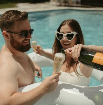 Couple avec des lunettes de soleil profitant d'un moment complice au bord d'une piscine.