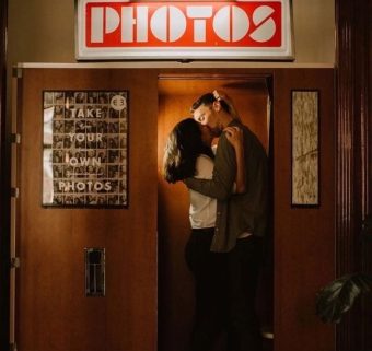 Couple s'embrassant dans une cabine photomaton au décor vintage.