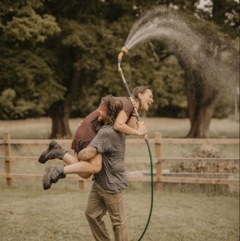 Couple s'amusant avec un jet d'eau dans un jardin