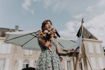 Une témoin de la mariée tenant un bouquet de fleurs colorées pendant le mariage en extérieur au Château Lacoste.