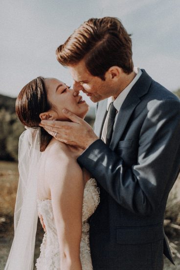 Le marié tenant tendrement le visage de son épouse pendant une séance photo de mariage en extérieur.
