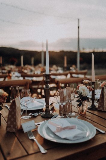 Décoration de réception avec longues tables en bois dressées dans le jardin du Château Lacoste.