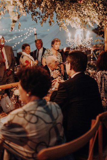 Réception de mariage en soirée avec longues tables dressées et éclairages suspendus dans le jardin du château.