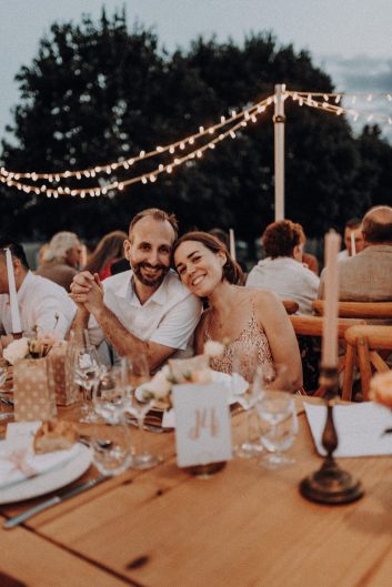 Deux invités souriants assis ensemble à une table pendant le dîner de mariage au Château Lacoste.