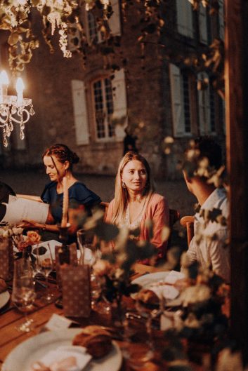 Deux invitées assises à une table de réception pendant une soirée de mariage au château.