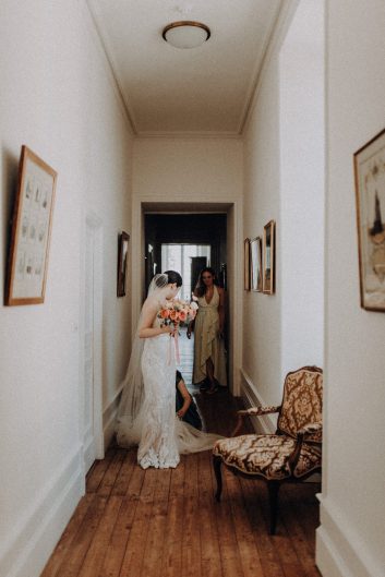 La mariée photographiée dans le couloir lumineux du château pendant les préparatifs de son mariage.