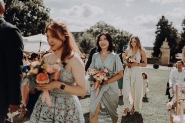 La mariée entourée de plusieurs femmes en robes élégantes dans le jardin du château.
