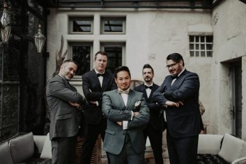 Château des Girards - Complicité entre les garçons Groupe d'hommes en costumes élégants discutant et riant dans la cour du château avant la cérémonie.