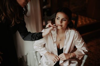 Château des Girards - Séance maquillage de la mariée Mariée assise en peignoir blanc pendant sa séance de maquillage avant le mariage.
