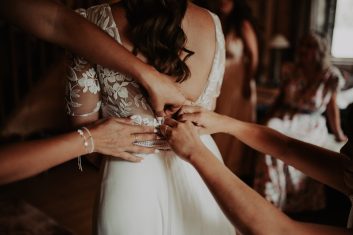 Château des Girards - Les derniers ajustements de la robe Plusieurs femmes aidant la mariée à ajuster sa robe de mariage en dentelle pendant les préparatifs.