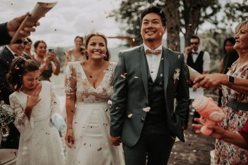 Château des Girards - La sortie des mariés Jeunes mariés souriants avançant au milieu de leurs invités après une cérémonie de mariage en extérieur.