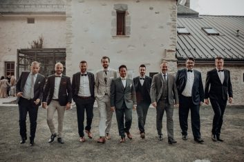 Château des Girards - Portrait de groupe des garçons Groupe d'hommes en costumes élégants posant ensemble devant les bâtiments en pierre du château.