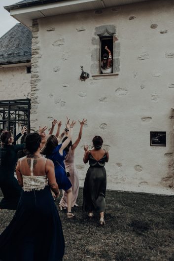 Château des Girards - Lancé de bouquet Groupe d'invités levant les bras pour attraper le bouquet devant un bâtiment en pierre du château.