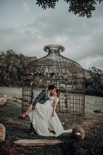Château des Girards - Un décor romantique dans le jardin Couple de mariés photographié devant une grande structure métallique en forme de cage dans le jardin du château.