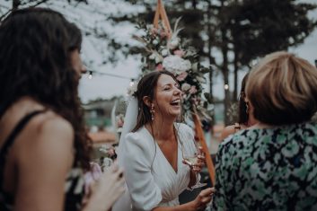 Photographe de mariage échangeant avec des invitées lors d'un cocktail en extérieur